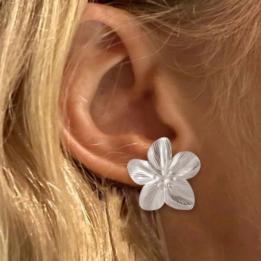 Boucles d'oreilles grande fleur en acier argenté portées par une femme, style élégant