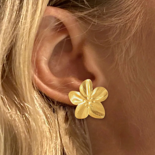 Boucles d'oreilles grande fleur en acier doré portées par une femme, style élégant