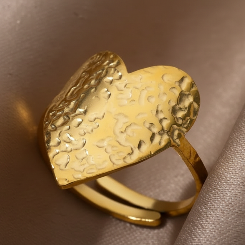 Gros plan sur une bague coeur stylisé et martelé en acier inoxydable doré.
