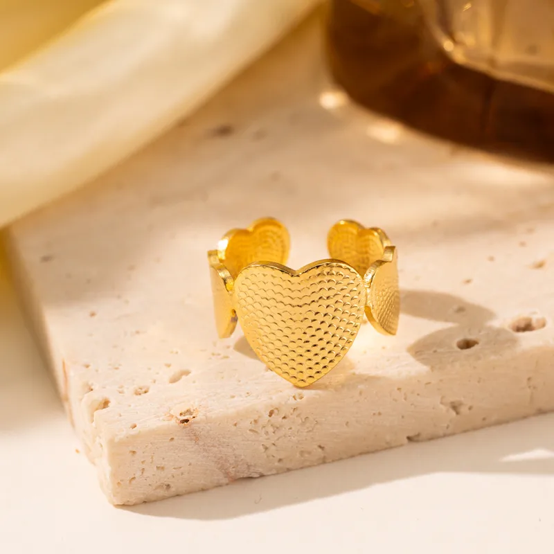 Bague dorée en acier inoxydable avec un cœur central et deux cœurs latéraux stylisés