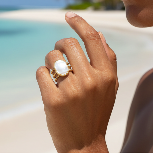 Main de femme portant une bague dorée en acier inoxydable ornée de nacre.