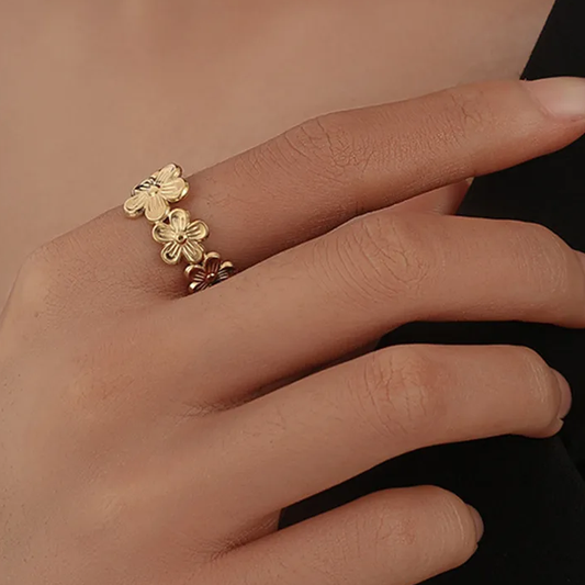 Bague ajustable en acier inoxydable avec fleurs dorées, portée sur la main d’une femme, bijou bohème