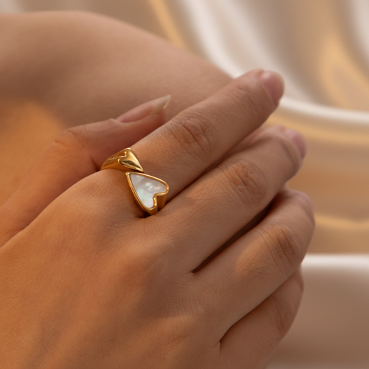 Main de femme portant une bague en acier inoxydable 316L doré avec un cœur en nacre.