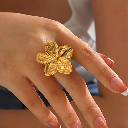 Bague dorée ajustable en acier inoxydable avec grande fleur tropicale, portée sur la main d’une femme, bijou bohème