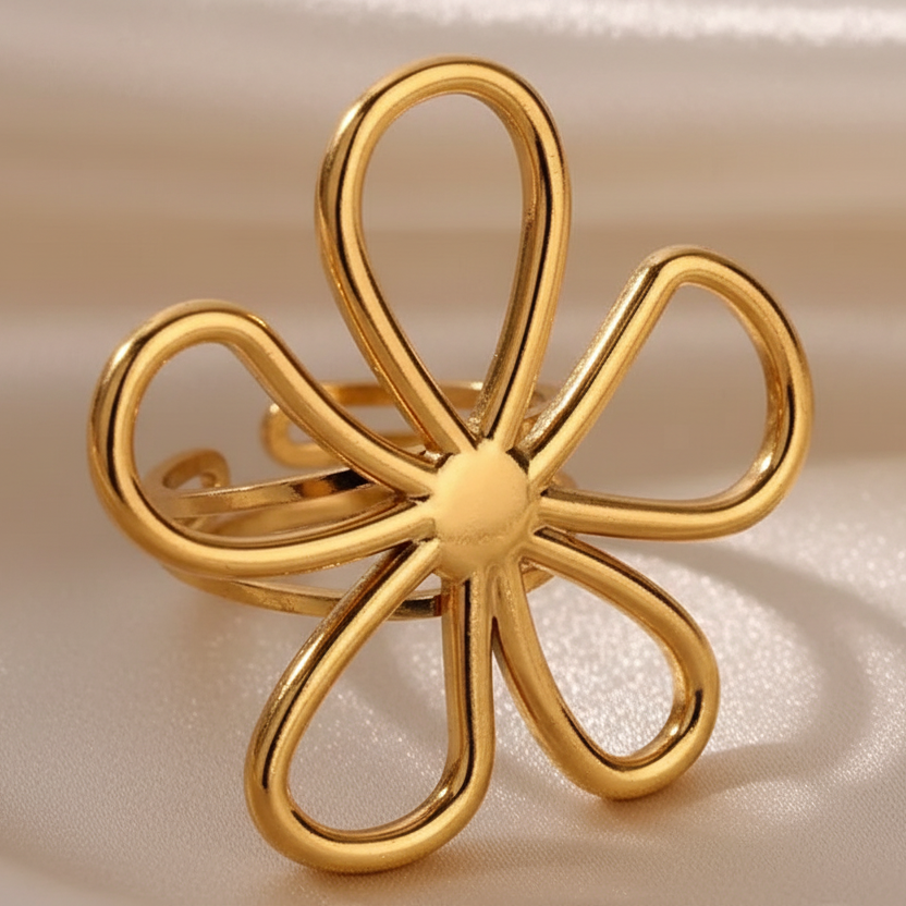 Gros plan sur une bague ajustable en acier inoxydable doré, ornée d’une grande fleur ajourée.