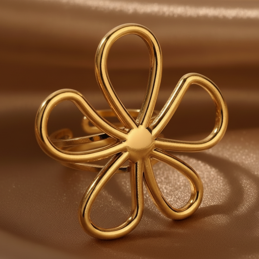 Gros plan sur une bague ajustable en acier inoxydable doré, ornée d’une grande fleur ajourée.
