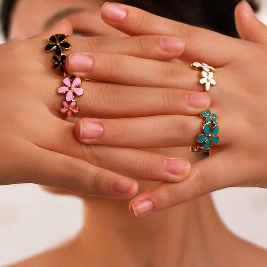 Bague dorée ajustable en acier inoxydable avec trois fleurs en émail, portée sur la main d’une femme, bijou bohème, disponible en bleu, rose, noir et blanc