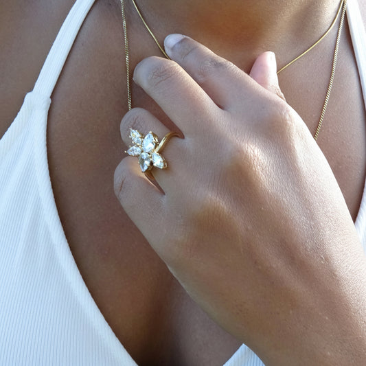 Bague fleur dorée en acier inoxydable 316L avec zircons blancs portée sur une main.