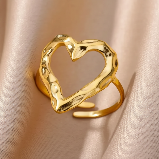 Gros plan sur une bague coeur stylisé ajouré et martelé en acier inoxydable doré.