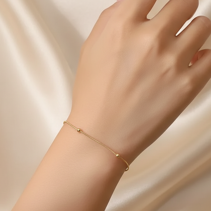 Femme portant un bracelet en acier inoxydable doré, fine maille serpent perlée, style bohème élégant
