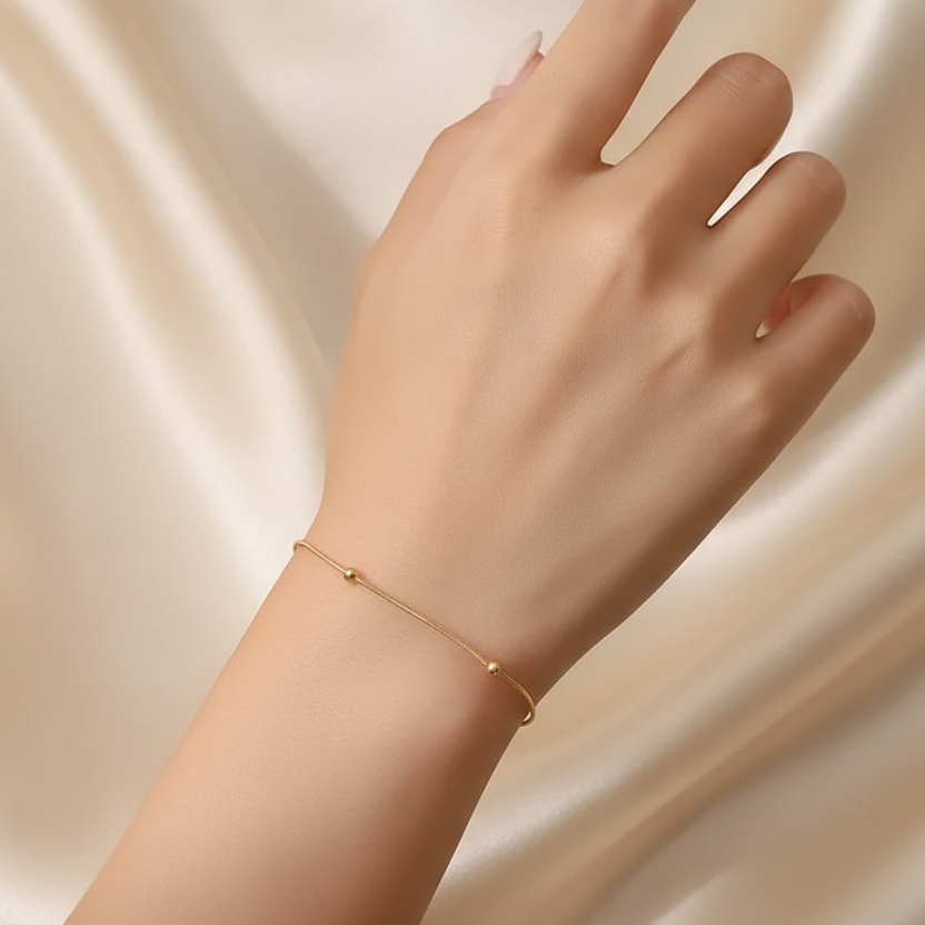 Femme portant un bracelet en acier inoxydable doré, fine maille serpent perlée, style bohème élégant