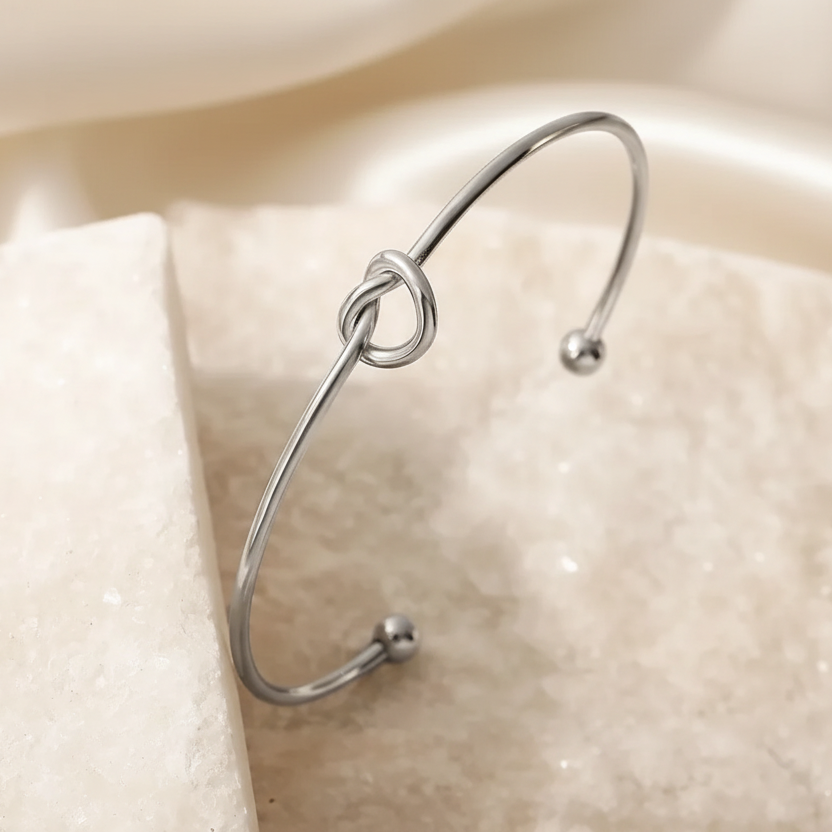 Bracelet manchette fin argenté en acier inoxydable, orné d’un cœur noué.