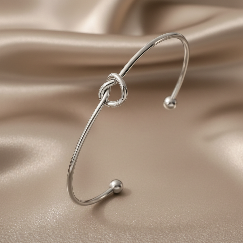 Bracelet manchette fin argenté en acier inoxydable, orné d’un cœur noué.