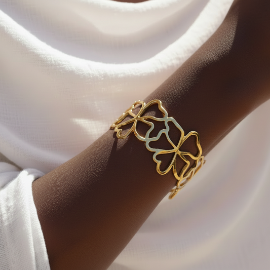 Poignet portant un bracelet manchette doré en acier inoxydable 316L avec fleurs ajourées.