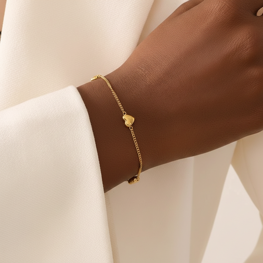 Bracelet doré en acier inoxydable 316L à fine maille gourmette orné de trois petits cœurs porté sur un poignet.
