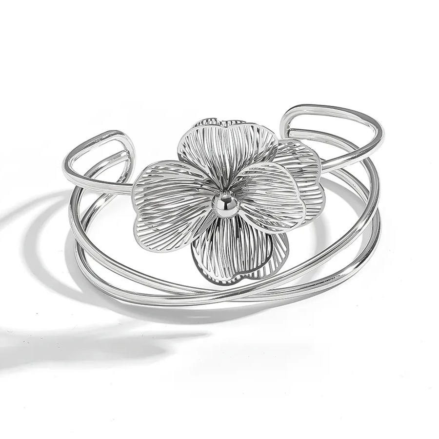 Gros plan sur un bracelet manchette en acier inoxydable 316L argenté, décoré d’une grande fleur stylisée.