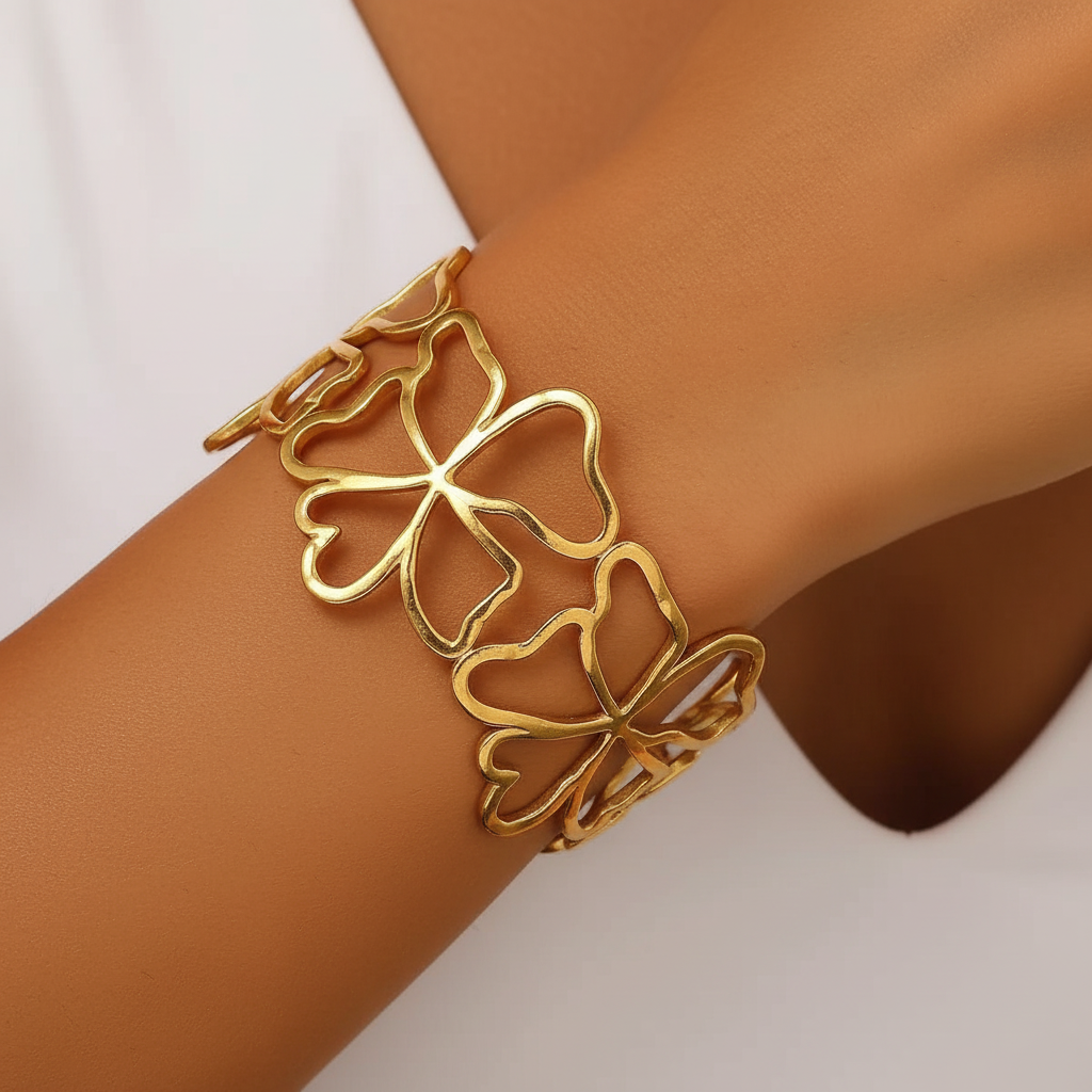 Gros plan d'un poignet portant un bracelet manchette doré en acier inoxydable 316L avec fleurs ajourées.