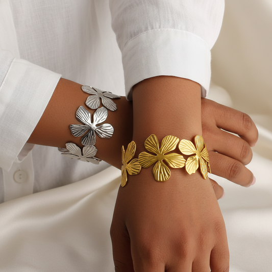 Femme portant un bracelet manchette large en acier inoxydable 316L argenté et doré, décoré de fleurs tropicales.