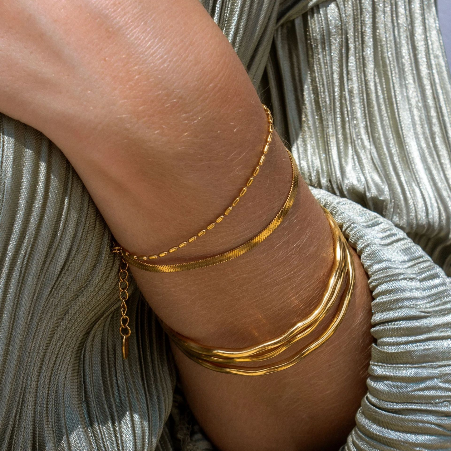 Femme portant des bracelets jonc fins ondulés en acier inoxydable 316L doré, style chic et bohème