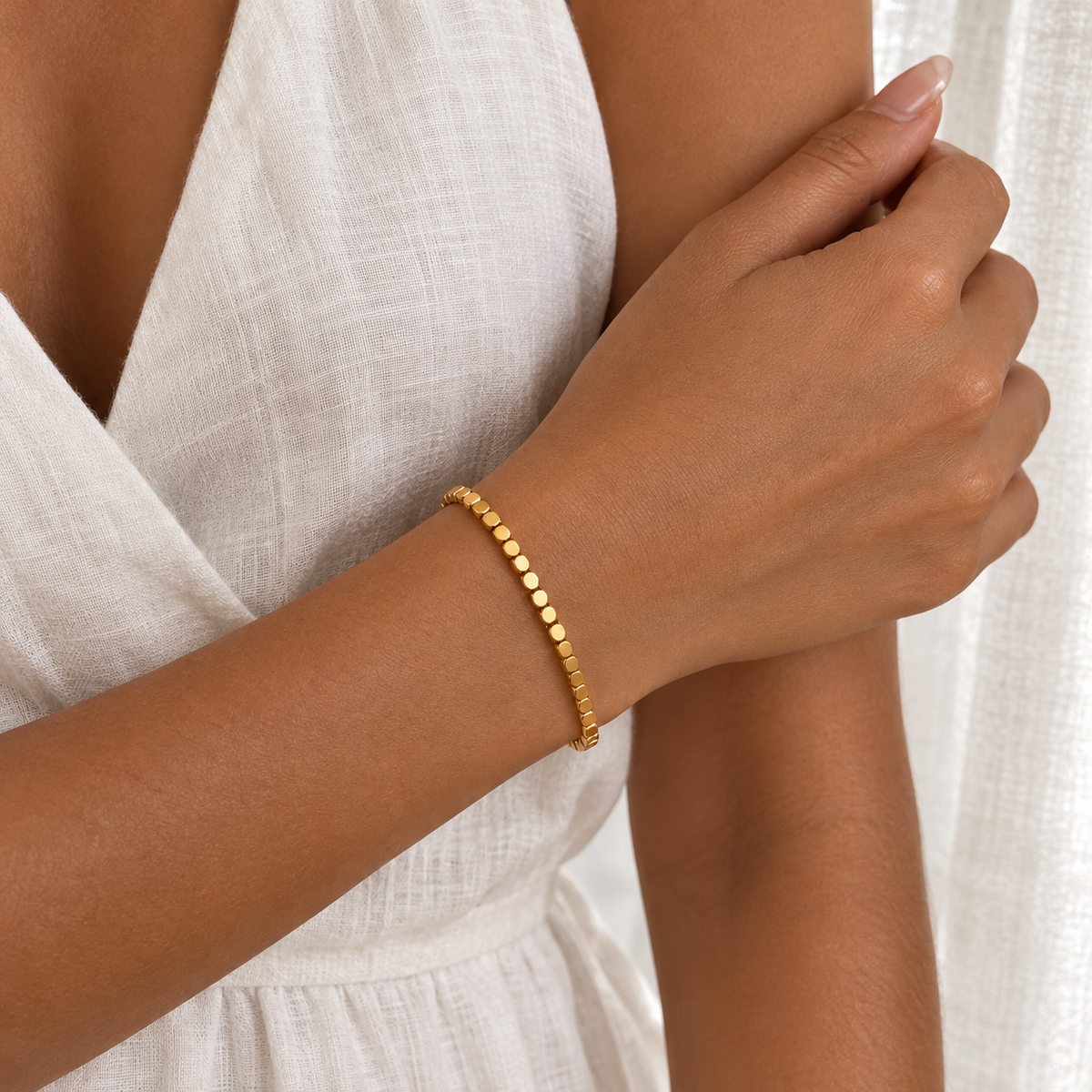 Bracelet chaîne à perles carrées en acier inoxydable 316L doré porté par une femme.
