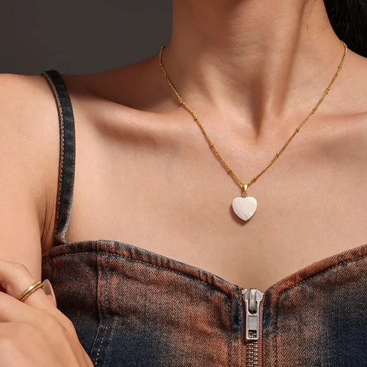 Femme portant un collier doré en acier inoxydable à maille gourmette perlée orné d’un pendentif cœur en nacre