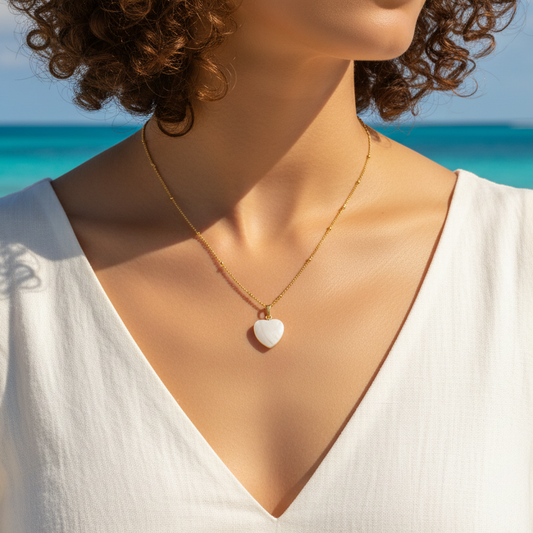 Femme portant un collier doré en acier inoxydable à maille gourmette perlée orné d’un pendentif cœur en nacre