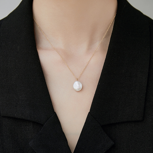 Femme portant un collier doré en acier inoxydable avec fine chaîne maille forçat et grosse perle d’eau douce