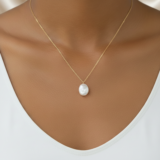 Femme portant un collier doré en acier inoxydable à fine chaîne maille forçat et grosse perle d’eau douce naturelle