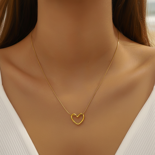 Femme portant un collier doré en acier inoxydable avec fine chaîne maille serpent et pendentif cœur ajouré