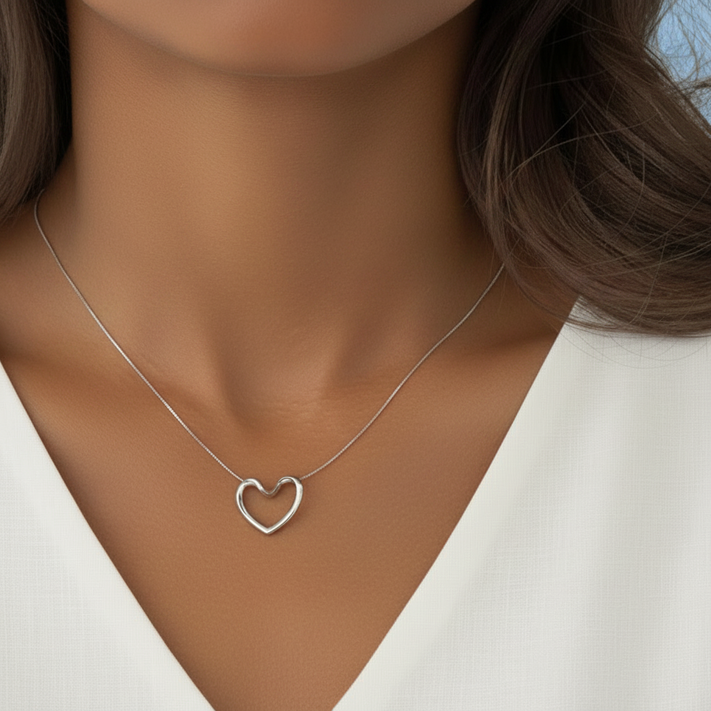 Femme portant un collier argenté en acier inoxydable 316L à fine chaîne maille serpent et pendentif cœur ajouré.