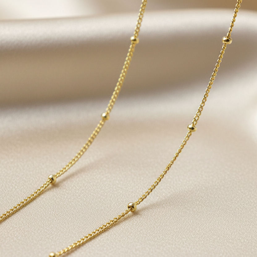 Zoom sur un collier doré en acier inoxydable à ultra fine maille gourmette et perles dorées pour femme, style minimaliste
