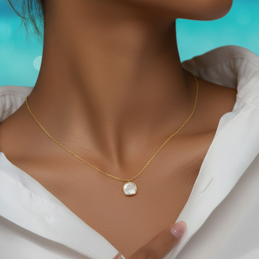 Femme portant un collier doré en acier inoxydable avec fine maille forçat et pendentif carré en nacre