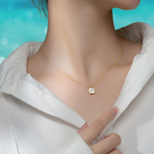 Femme portant un collier doré en acier inoxydable avec fine maille forçat et pendentif carré en nacre