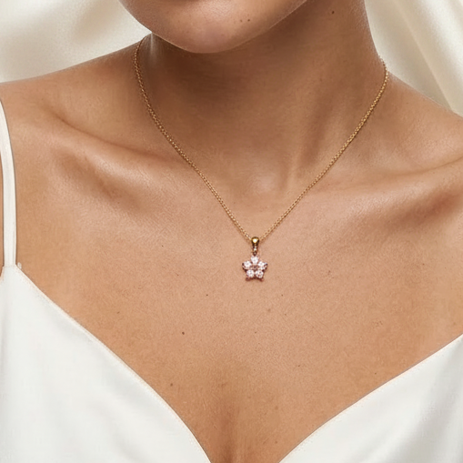 Femme portant un collier doré en acier inoxydable 316L orné d'un pendentif petite fleur à 5 pétales en zirconia blanc.