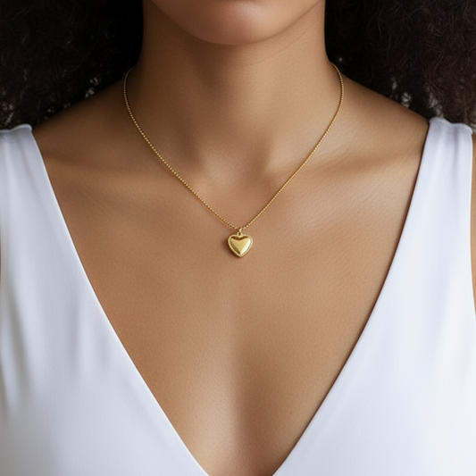 Collier doré en acier inoxydable 316L avec petit pendentif cœur et chaîne fine à billes, porté sur le cou d'une femme.