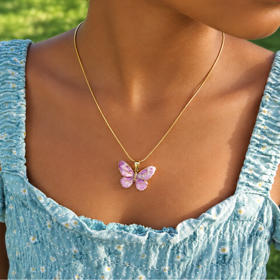 Enfant portant un collier en acier inoxydable 316 L doré avec pendentif papillon en émail rose et violet et sa chaîne fine maille serpent.