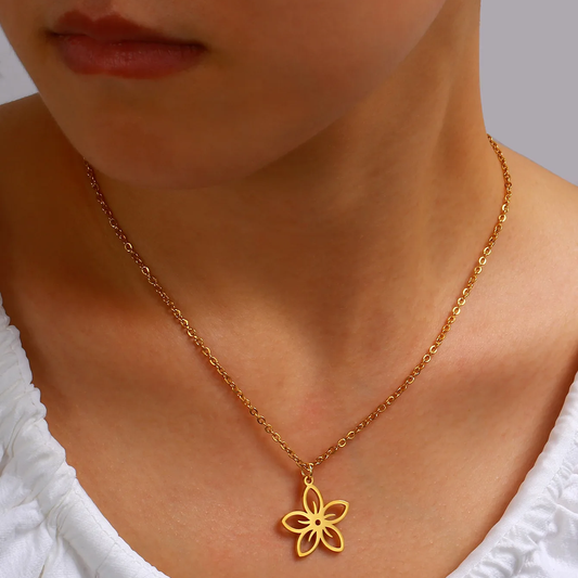 Femme portant un collier doré en acier inoxydable avec pendentif fleur stylisée, bijou bohème