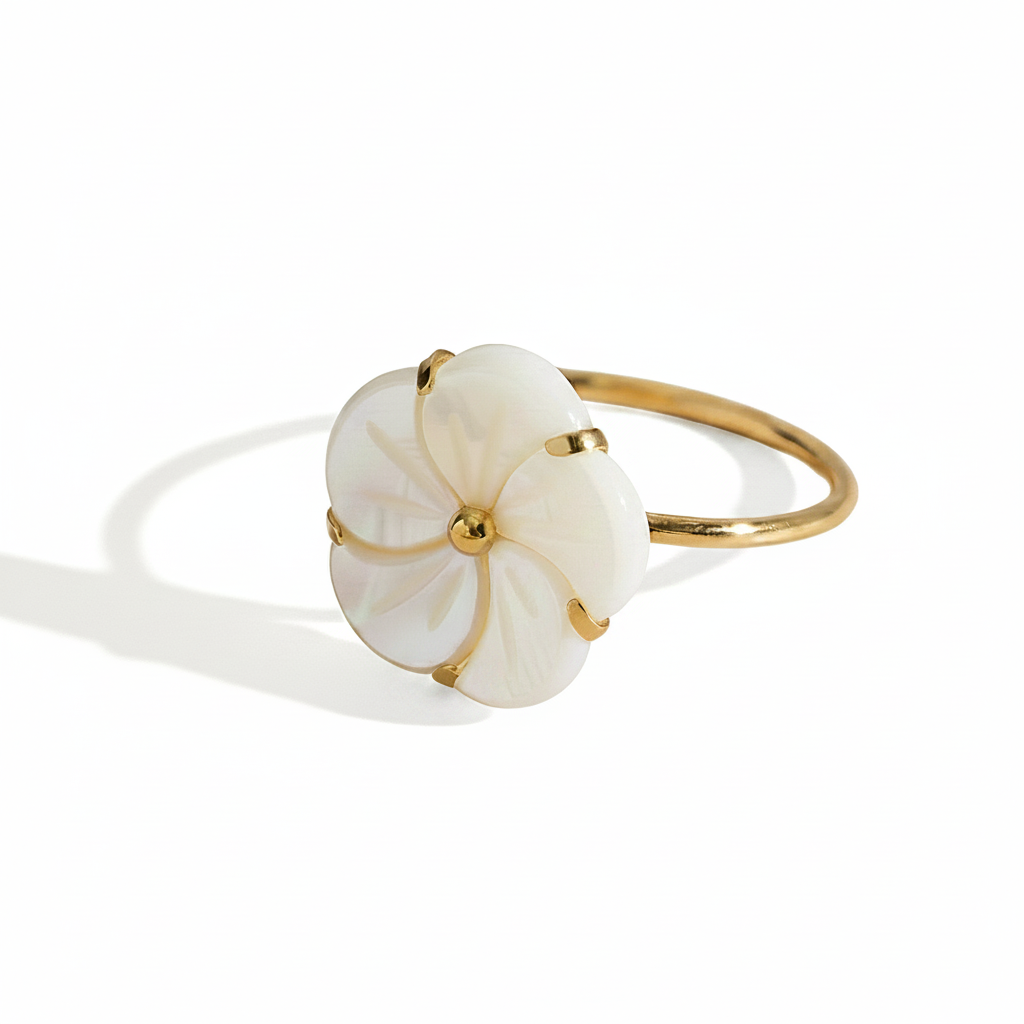 Gros plan sur une bague dorée en acier inoxydable ornée d’une fleur en nacre.