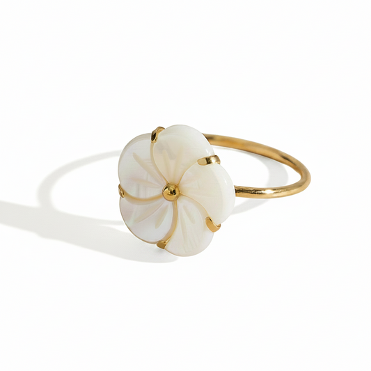 Gros plan sur une bague dorée en acier inoxydable ornée d’une fleur en nacre.