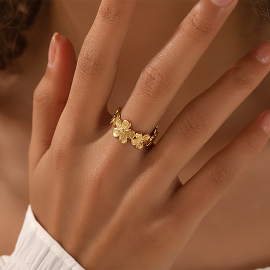 Bague ajustable en acier inoxydable doré, ornée d'une couronne de fleurs, portée sur une main.