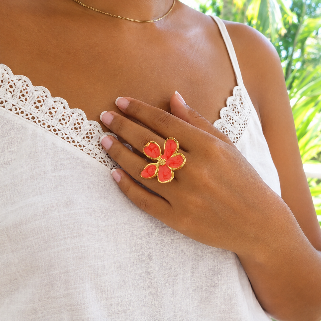 Femme portant une bague dorée ajustable en acier inoxydable, ornée d’une grande fleur en émail rouge.