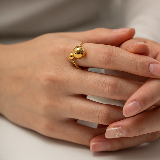 Bague dorée en acier inoxydable avec grande perle et petite perle en acier, portée sur la main d’une femme, bijou bohème
