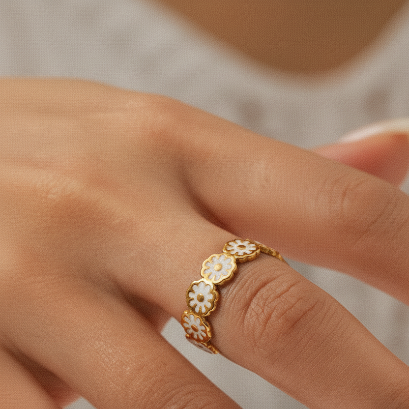 Bague ajustable en acier inoxydable doré, en couronne de fleurs émaillées blanches, bijou bohème et tendance floral sur la main d'une femme