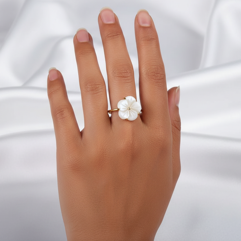 Bague dorée en acier inoxydable avec une fleur en nacre au style romantique et bohème portée sur la main d'une femme