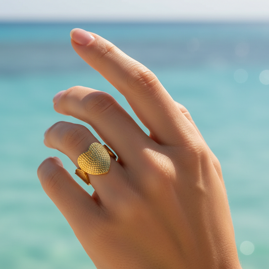 Bague avec un cœur central et deux cœurs latéraux stylisés en acier inoxydable 316L doré sur une main de femme.