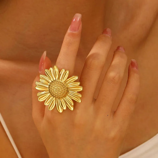 Bague tendance ajustable en acier inoxydable doré, avec grande fleur marguerite, portée sur la main d’une femme