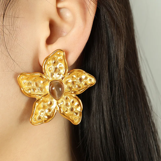Femme portant une boucle d’oreilles grande fleur tropicale 4,3 cm en acier inoxydable doré martelé avec cœur œil de tigre, style bohème
