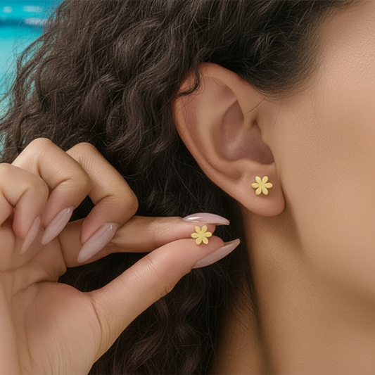 Femme portant des boucles d'oreilles tendance fleur stylisée en acier inoxydable doré, puce 0,8 cm, style minimaliste
