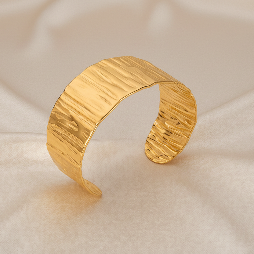 Bracelet manchette large de 3 cm en acier inoxydable doré, finition martelée et brillante.