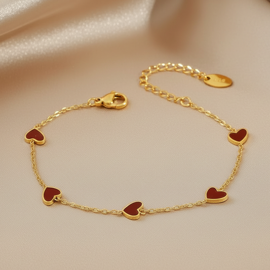 Bracelet doré en acier inoxydable à chaîne fine orné de 5 coeurs en résine rouge.